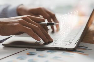 Person tippt auf Laptoptastatur und hält wichtige Dokumente aktuell
