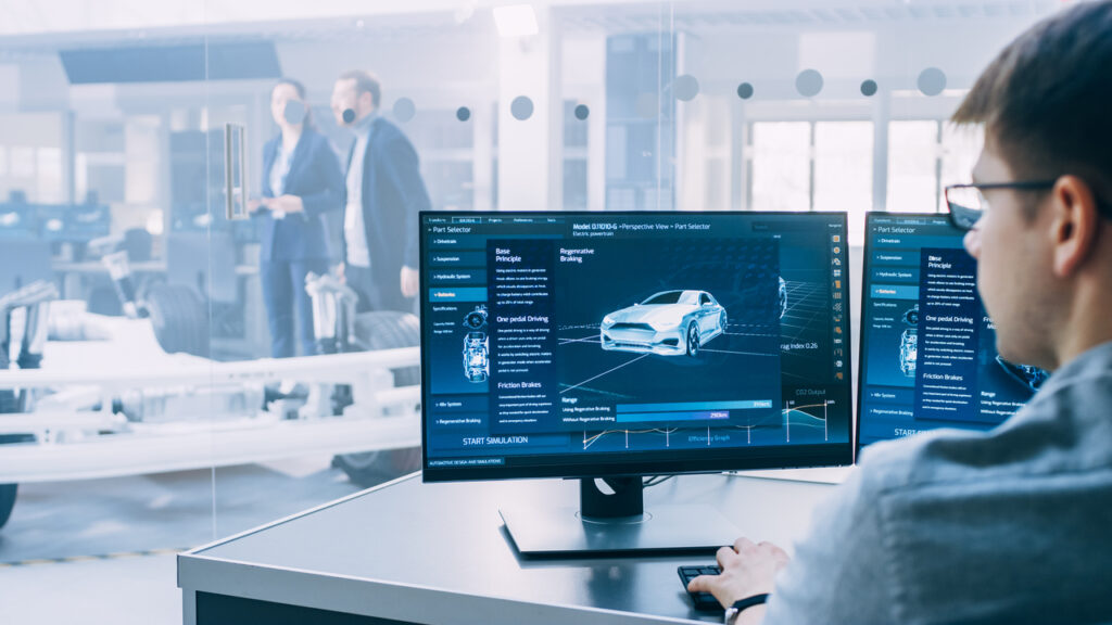 Mitarbeiter vor Bildschirm mit digitalem Fahrzeugmodell in moderner Entwicklungsumgebung